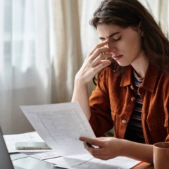 Pessoa sentada com express&atilde;o de cansa&ccedil;o, apoiando a cabe&ccedil;a nas m&atilde;os, indicando fadiga no dia a dia.
