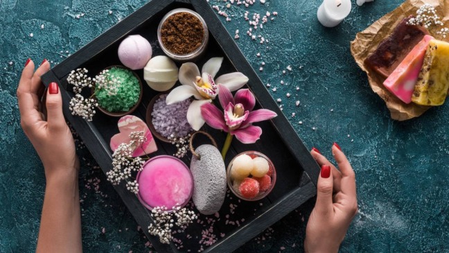 Close em sais de banho minerais ao lado de toalha e vela, simbolizando autocuidado.