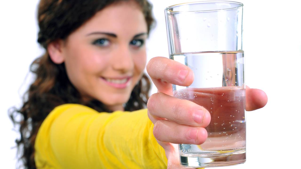 Pessoa segurando copo de água, representando cuidado com o corpo e redução do desejo por doces.