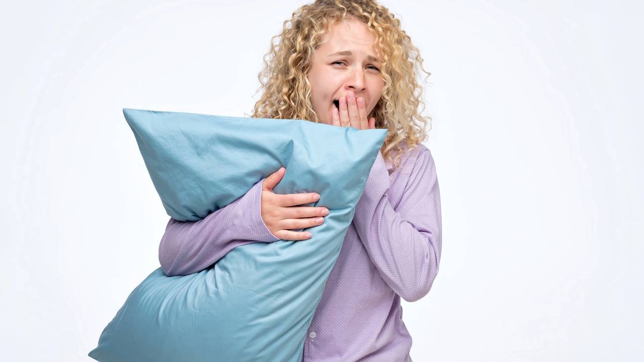 Pessoa acordada na cama durante a noite, representando falta de sono e bem-estar em baixa