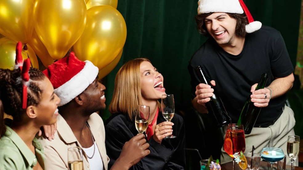 Uma família reunida ao redor da mesa brinca com biscoitos, copos e doces de Natal, rindo enquanto participa de desafios simples e acessíveis que usam materiais comun Uma família reunida ao redor da mesa brinca com biscoitos, copos e doces de Natal, rindo enquanto participa de desafios simples e acessíveis que usam materiais comun