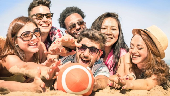 Pessoas jogando jogos de praia na areia para se manter ativas de forma leve e divertida