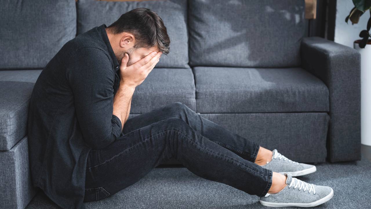 Pessoa pensativa olhando para baixo, representando autoestima inst&aacute;vel e medo de errar diante de pequenas falhas.