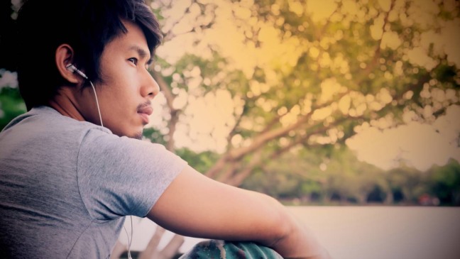 Pessoa com fones de ouvido em momento de introspecção usando música melancólica para lidar com a dor emocional.