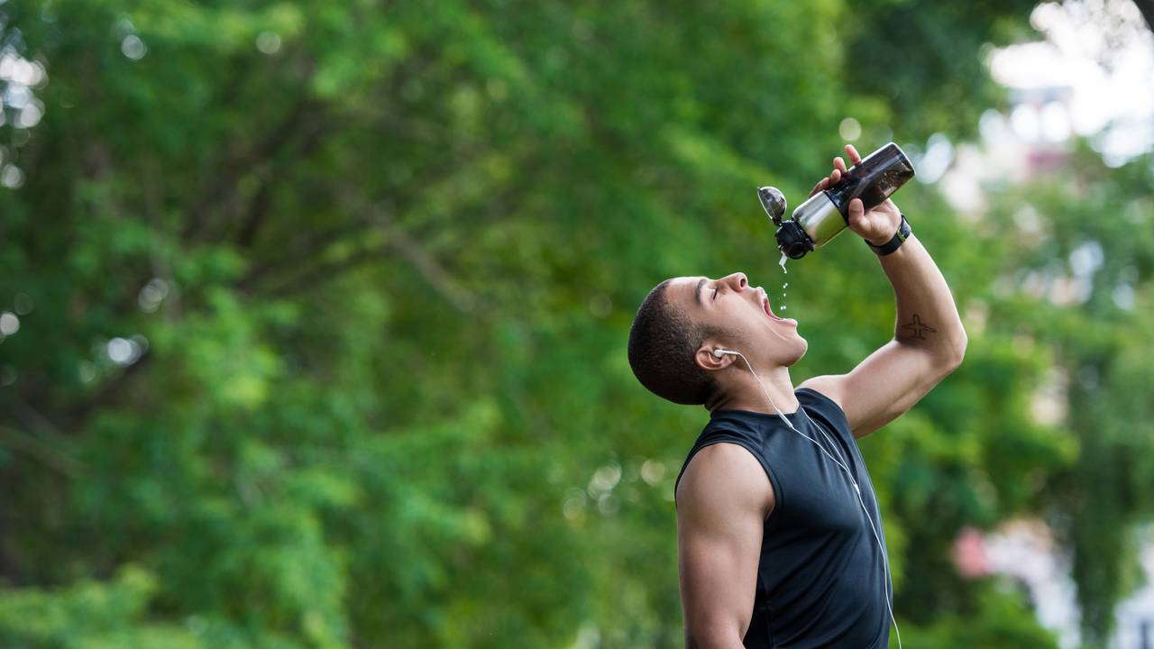 Pessoa bebendo água antes de praticar exercícios físicos, mostrando preparo e energia.