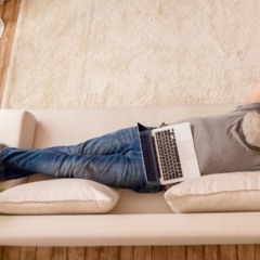 Pessoa deitada no sof&aacute; tentando descansar enquanto demonstra express&atilde;o de culpa e inquieta&ccedil;&atilde;o