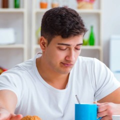 Pessoa apoiando a cabeça na mesa de escritório, com expressão de cansaço logo após o almoço.
