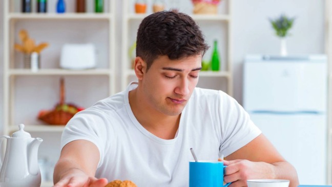 Pessoa apoiando a cabeça na mesa de escritório, com expressão de cansaço logo após o almoço.