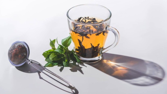 Xícara de chá quente preparada com ervas naturais para promover sensação de bem-estar