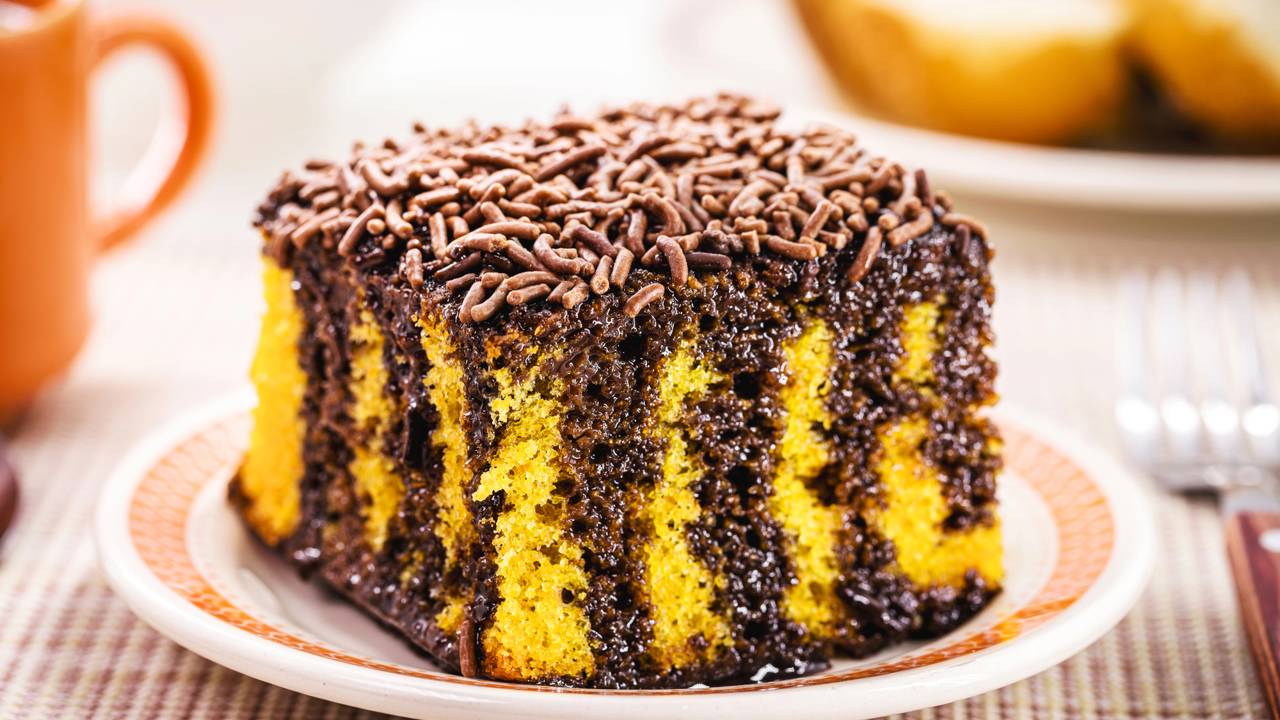 Bolo de cenoura fofinho com cobertura de chocolate escorrendo pelas laterais.