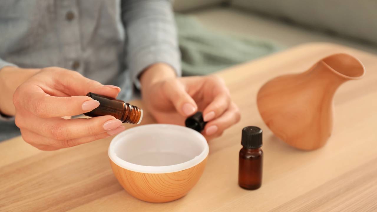 Frasco de difusor com varetas inseridas, espalhando fragr&acirc;ncia de &oacute;leos essenciais no ambiente.