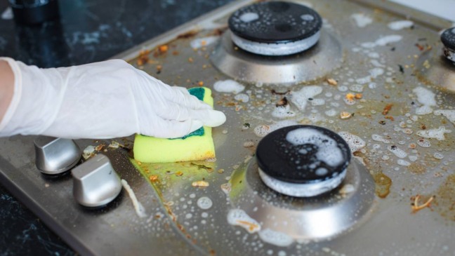 Fogão com gordura acumulada e respingos de comida antes da limpeza na cozinha.