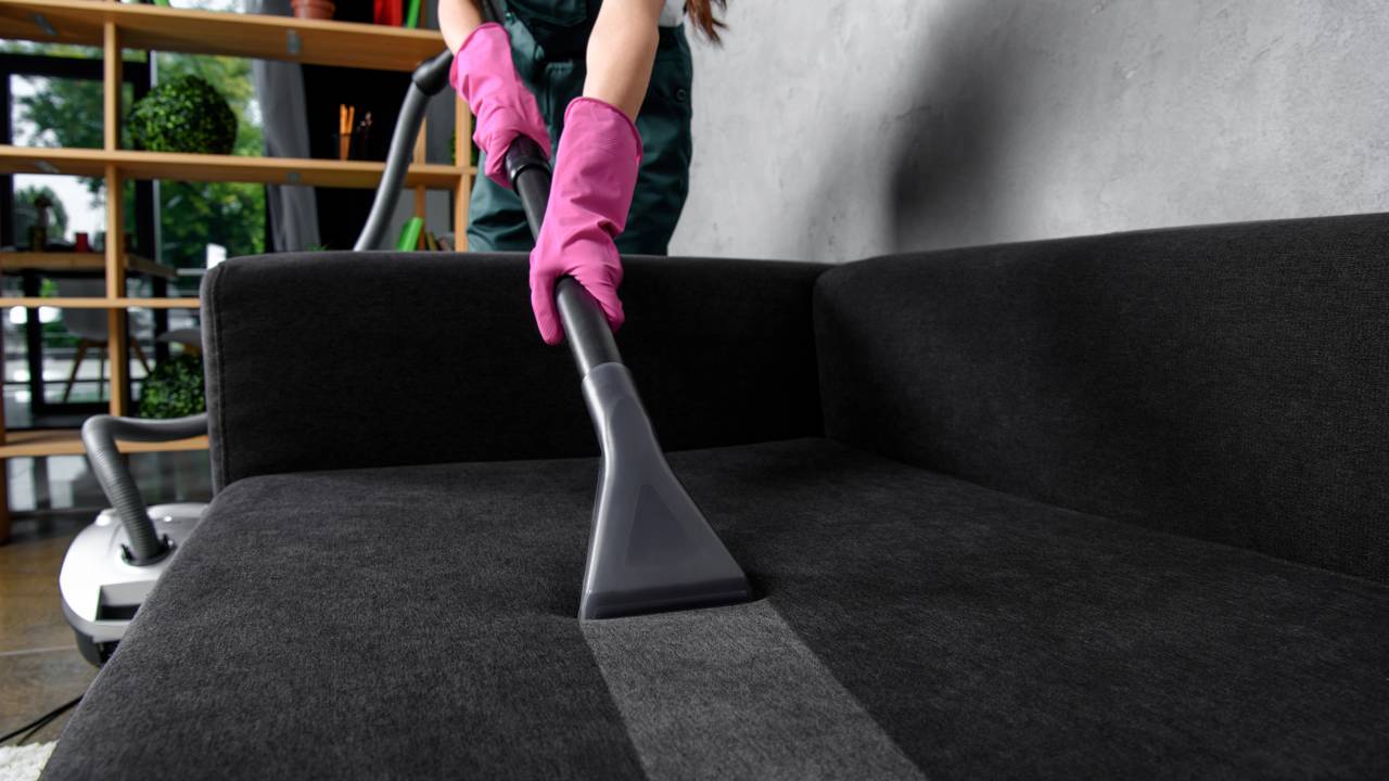 Pessoa usando aspirador de p&oacute; para limpar pisos, tapetes e reduzir poeira que poderia se depositar em m&oacute;veis e superf&iacute;cies.