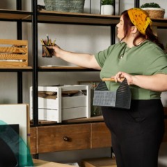 Mulher organizando prateleiras e objetos em um ambiente compacto.