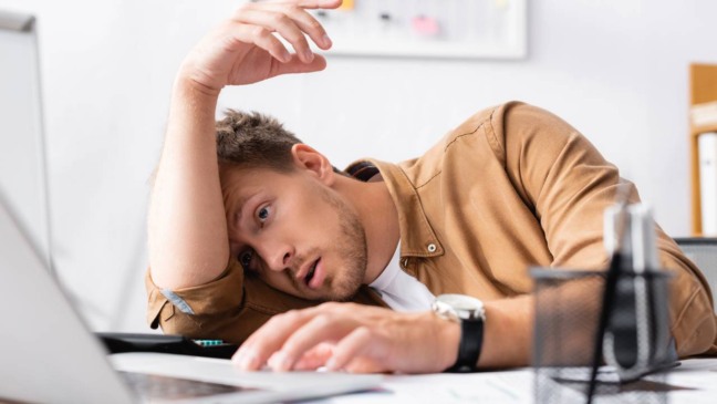 Indivíduo sentado com postura abatida indicando esgotamento mental