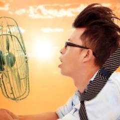 Pessoa sentindo calor dentro de casa em Niterói usando ventilador para aliviar altas temperaturas causadas pelo sol forte.