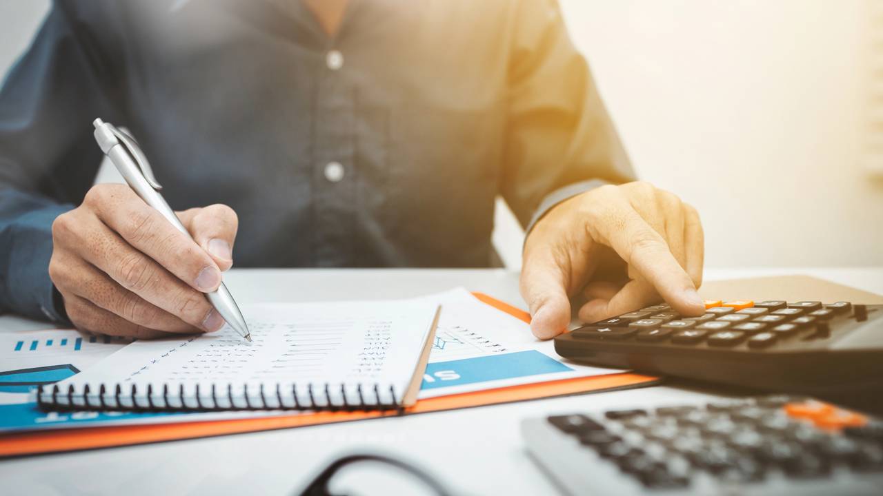 Pessoa planejando or&ccedil;amento de constru&ccedil;&atilde;o de loft moderno no RJ com gr&aacute;ficos e planilhas de custos