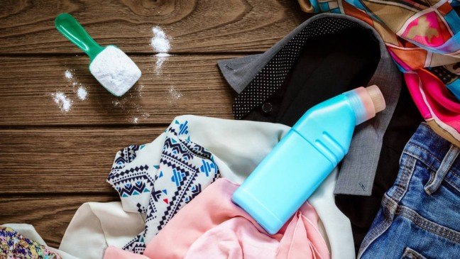 Pessoa mexendo água, amaciante concentrado e álcool em recipiente limpo para fazer spray caseiro de roupas.