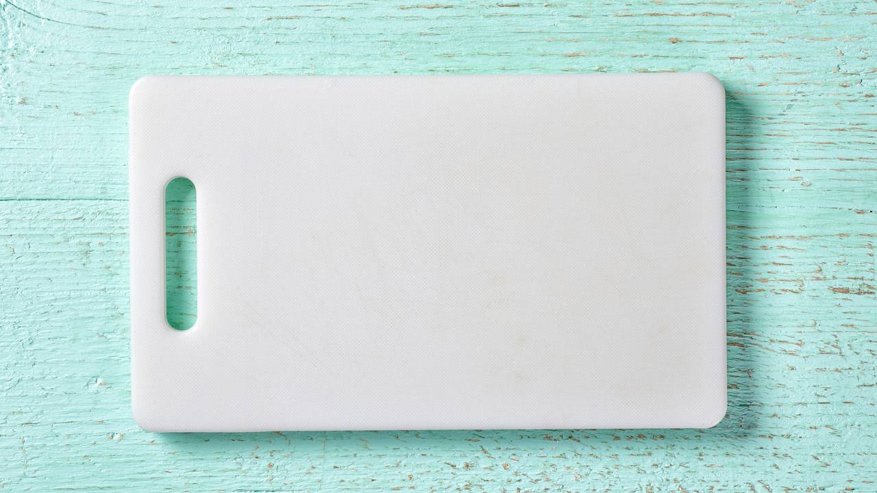 T&aacute;bua de corte de pl&aacute;stico em superf&iacute;cie de cozinha, pronta para preparar alimentos com seguran&ccedil;a.